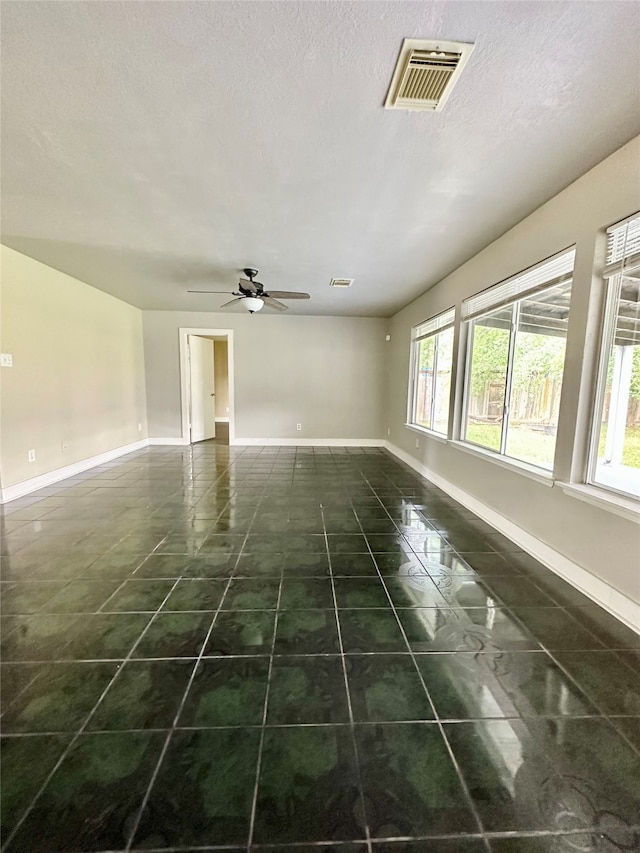 tiled empty room featuring ceiling fan and a textured ceiling