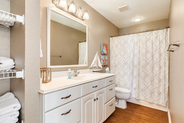 bathroom featuring a textured ceiling, toilet, hardwood / wood-style floors, vanity, and curtained shower