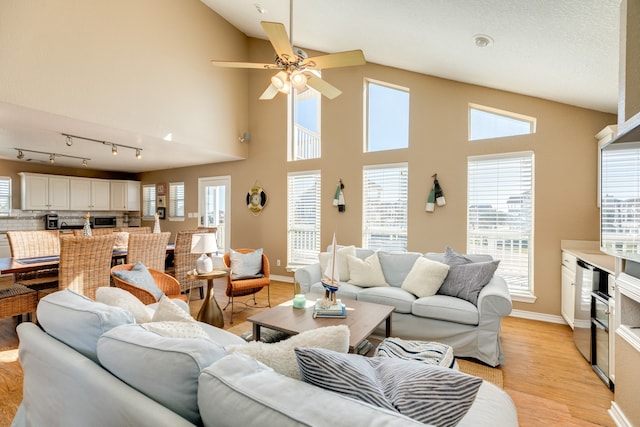 living room featuring light wood-type flooring, ceiling fan, and high vaulted ceiling