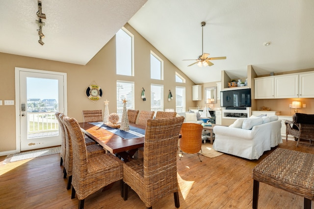 dining room with ceiling fan, light hardwood / wood-style flooring, high vaulted ceiling, and a wealth of natural light