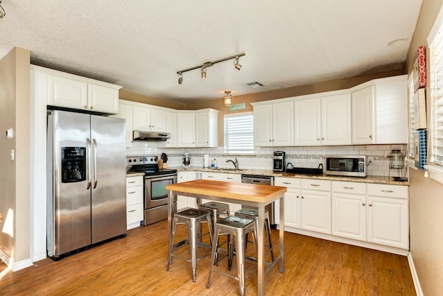 kitchen featuring tasteful backsplash, light hardwood / wood-style flooring, stainless steel appliances, and white cabinets