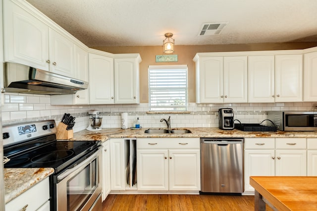 kitchen with white cabinets, appliances with stainless steel finishes, light wood-type flooring, and sink