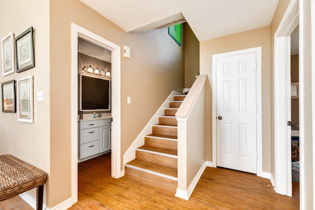 staircase featuring wood-type flooring and a textured ceiling