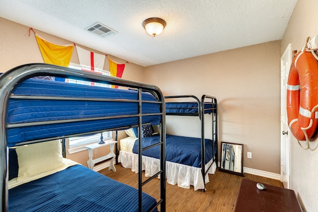 bedroom with a textured ceiling and dark hardwood / wood-style flooring