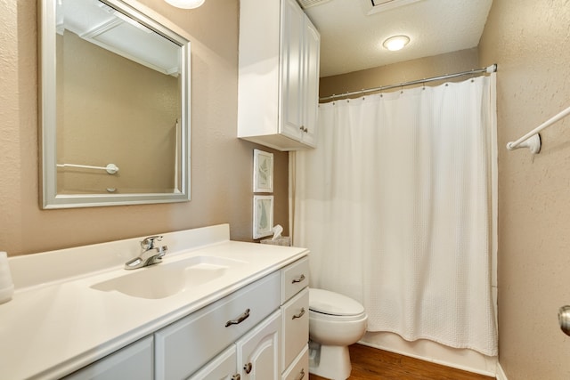 bathroom with a textured ceiling, a shower with shower curtain, hardwood / wood-style floors, vanity, and toilet