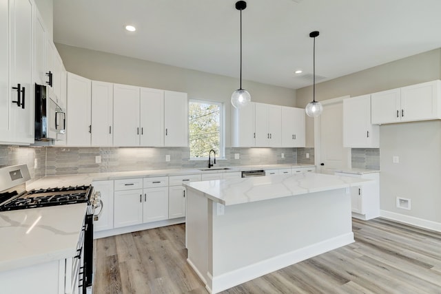 kitchen with a kitchen island, white cabinetry, sink, and appliances with stainless steel finishes