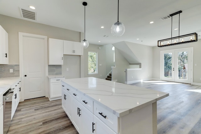 kitchen featuring french doors, backsplash, white cabinetry, and hanging light fixtures