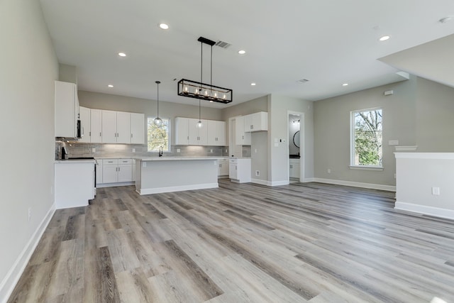 kitchen with a center island, plenty of natural light, white cabinets, and light hardwood / wood-style flooring