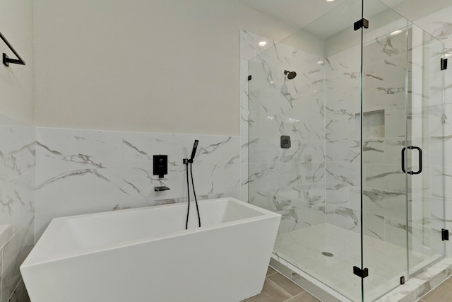 bathroom with tile patterned floors, shower with separate bathtub, and tile walls