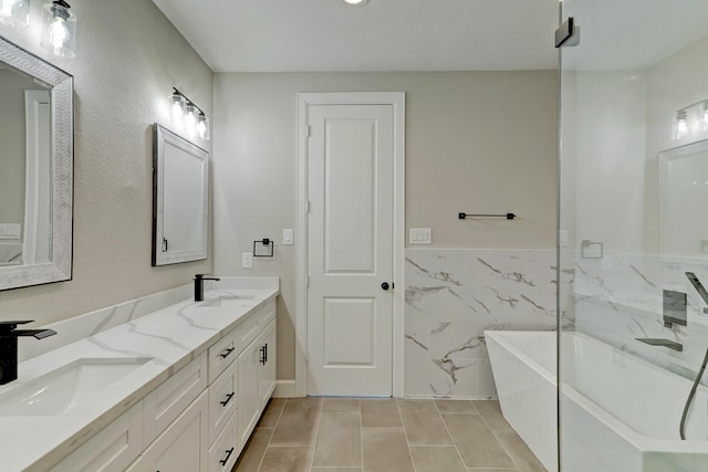 bathroom featuring a washtub, vanity, tile walls, and tile patterned flooring