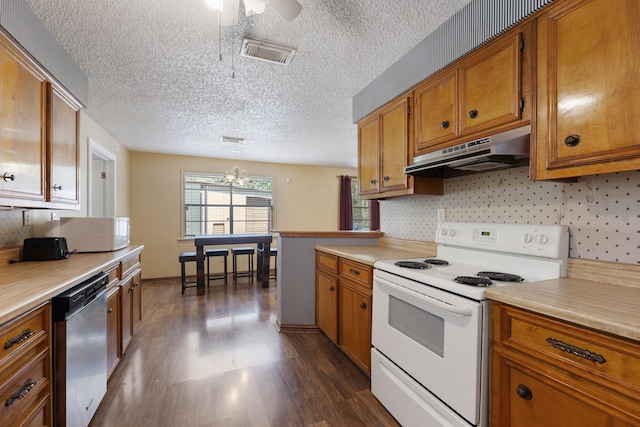 kitchen with hanging light fixtures, white appliances, dark wood-type flooring, ceiling fan, and a textured ceiling