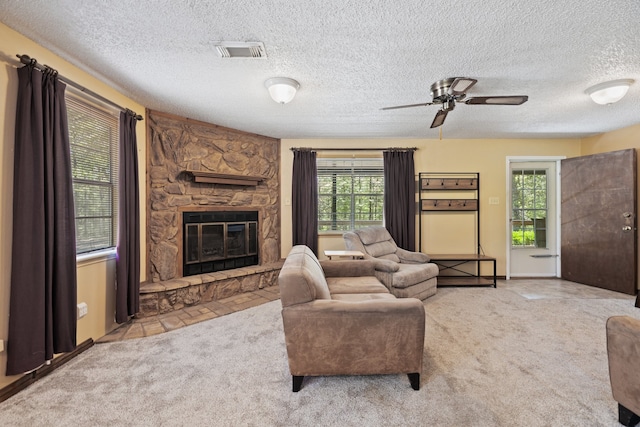 carpeted living room featuring a textured ceiling, plenty of natural light, ceiling fan, and a stone fireplace