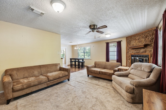 carpeted living room featuring a textured ceiling, ceiling fan, and a fireplace