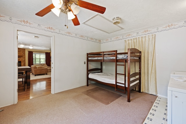 bedroom featuring light wood-type flooring, a textured ceiling, ceiling fan, and washer / clothes dryer