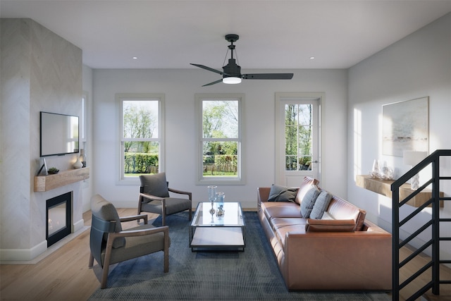 living room with a large fireplace, ceiling fan, and hardwood / wood-style flooring