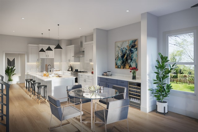 dining space with beverage cooler, light hardwood / wood-style flooring, and sink