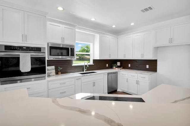 kitchen featuring appliances with stainless steel finishes, sink, white cabinets, and backsplash