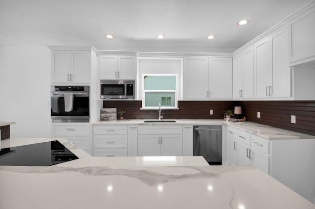 kitchen with sink, white cabinets, stainless steel appliances, and decorative backsplash