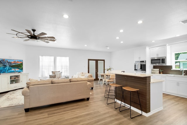 kitchen with a center island, a breakfast bar area, white cabinets, stainless steel microwave, and ceiling fan