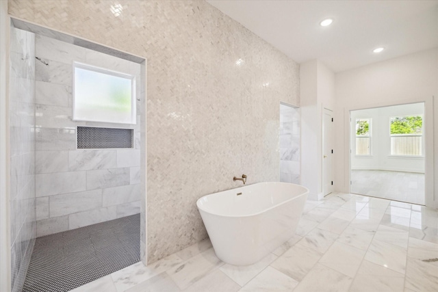 bathroom with tile walls and independent shower and bath