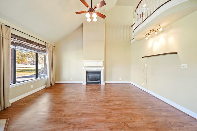 unfurnished living room featuring wood-type flooring, high vaulted ceiling, and ceiling fan