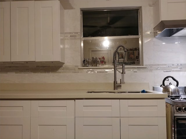 bar featuring white range oven, tasteful backsplash, sink, and white cabinetry