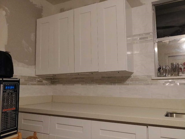 kitchen with tasteful backsplash and white cabinetry