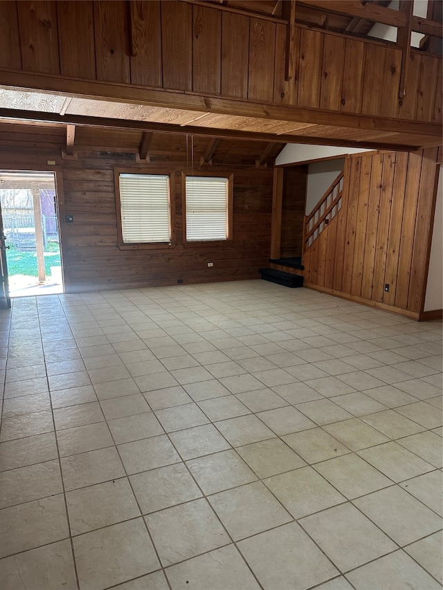 spare room with wood walls, light tile patterned floors, and beamed ceiling