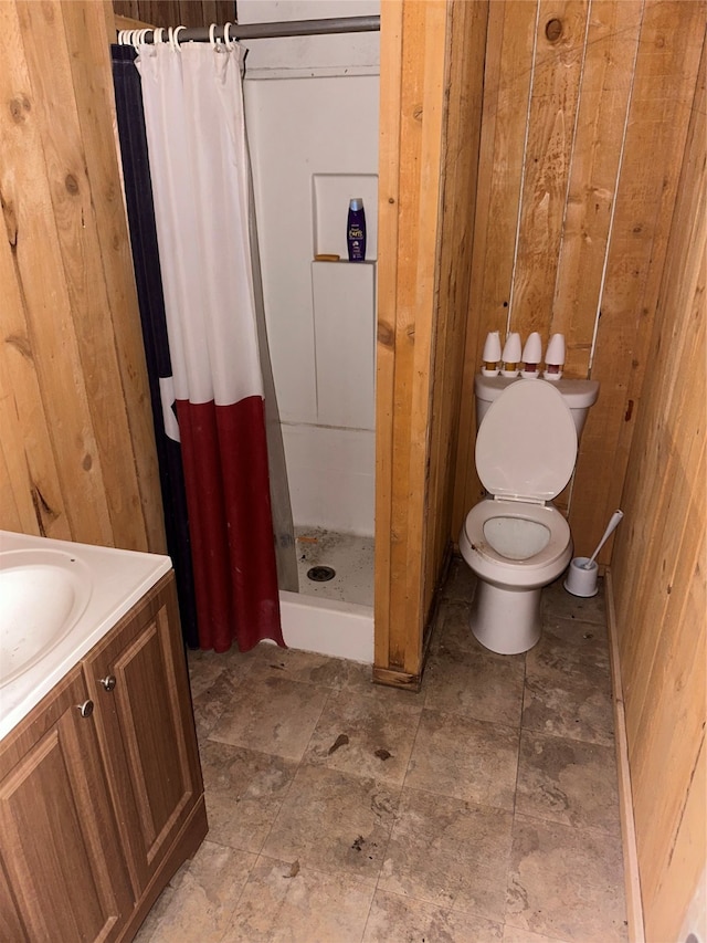 bathroom with vanity, toilet, curtained shower, and wooden walls