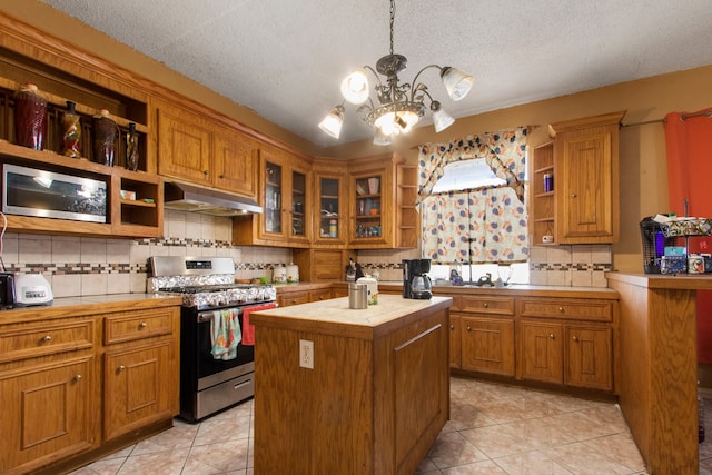 kitchen with light tile patterned flooring, stainless steel range, pendant lighting, decorative backsplash, and a kitchen island