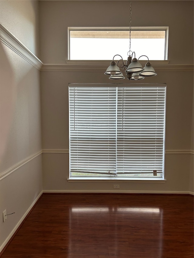 unfurnished dining area featuring a notable chandelier, dark hardwood / wood-style flooring, and ornamental molding