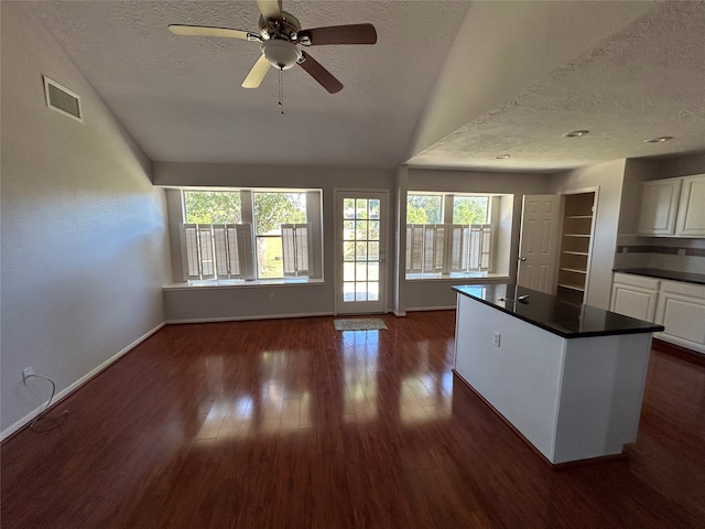 kitchen with ceiling fan, white cabinetry, a kitchen island, and dark wood-type flooring