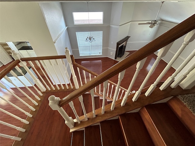 staircase with ceiling fan with notable chandelier, hardwood / wood-style flooring, and a towering ceiling