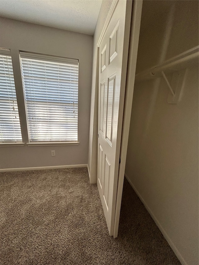 unfurnished bedroom featuring dark carpet and multiple windows