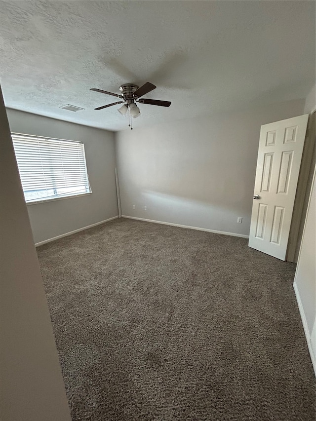 unfurnished room with dark colored carpet, a textured ceiling, and ceiling fan