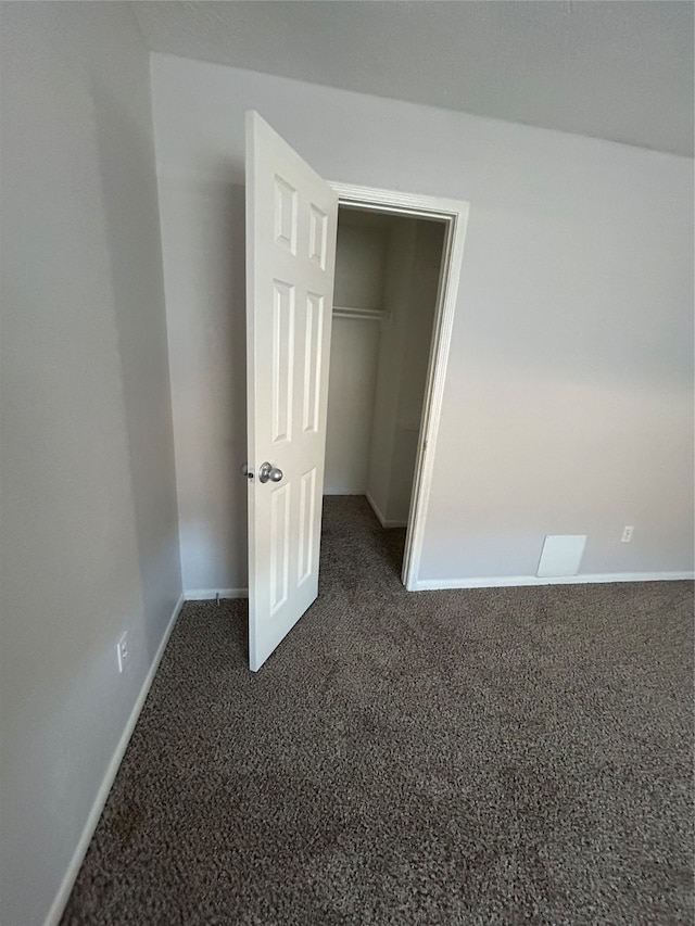 unfurnished bedroom featuring dark colored carpet and a closet