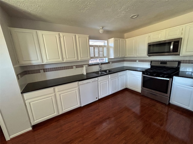 kitchen featuring white cabinetry, tasteful backsplash, dark wood-type flooring, stainless steel appliances, and sink