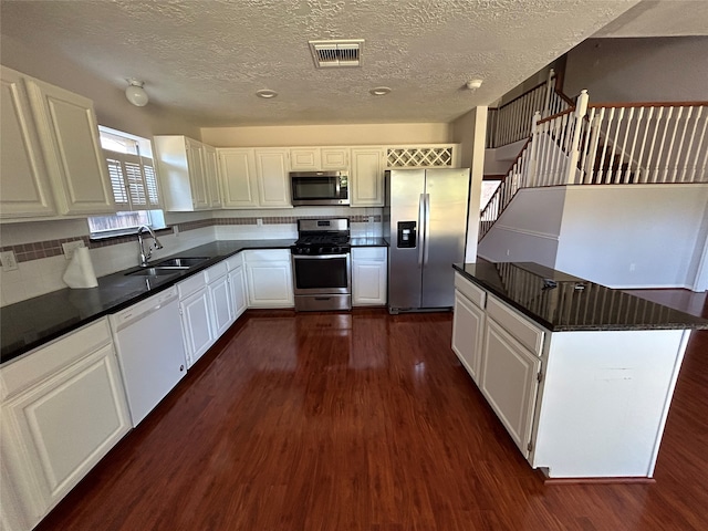 kitchen with white cabinetry, a textured ceiling, dark hardwood / wood-style floors, appliances with stainless steel finishes, and sink