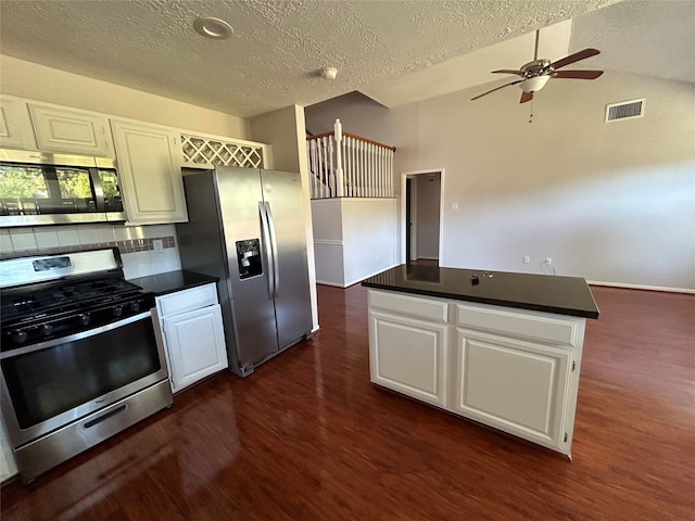 kitchen with appliances with stainless steel finishes, tasteful backsplash, white cabinets, and dark wood-type flooring