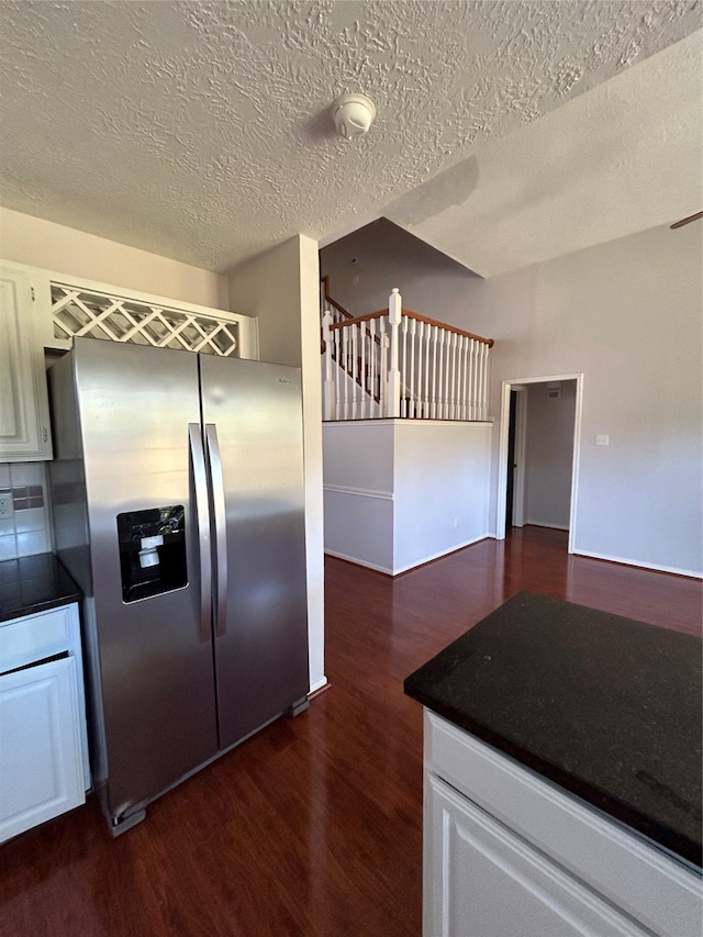 kitchen featuring stainless steel refrigerator with ice dispenser, a textured ceiling, white cabinets, and dark wood-type flooring