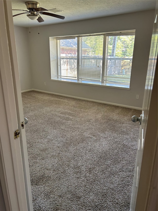 spare room with carpet flooring, a healthy amount of sunlight, a textured ceiling, and ceiling fan