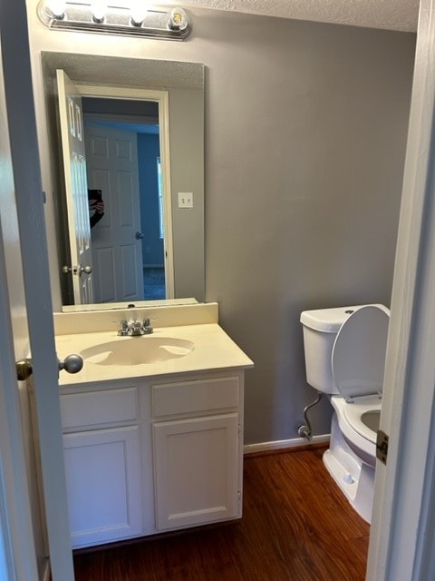 bathroom featuring hardwood / wood-style flooring, toilet, vanity, and a textured ceiling