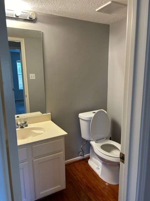 bathroom featuring vanity, a textured ceiling, toilet, and hardwood / wood-style floors