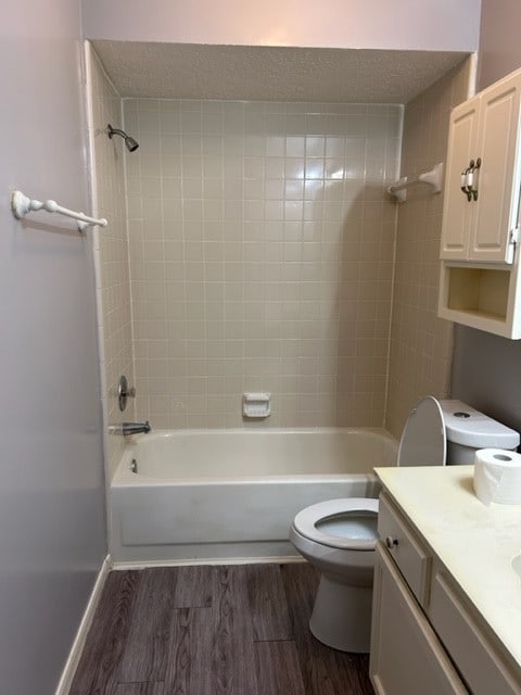 full bathroom featuring hardwood / wood-style flooring, toilet, vanity, and tiled shower / bath