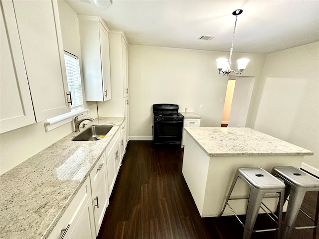 kitchen featuring black gas range oven, sink, white cabinets, dark hardwood / wood-style floors, and hanging light fixtures