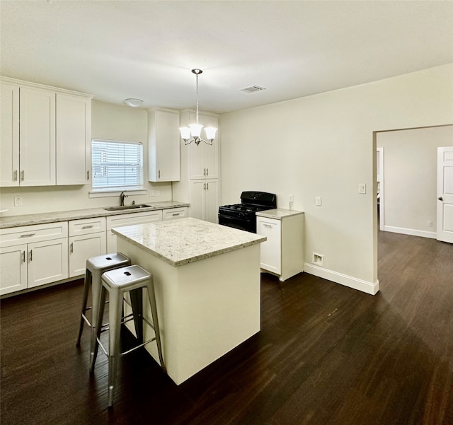 kitchen with pendant lighting, black gas stove, a kitchen island, dark hardwood / wood-style flooring, and white cabinetry