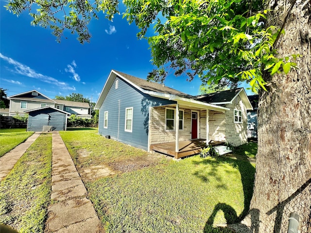 bungalow-style home featuring a porch, a front lawn, and a shed