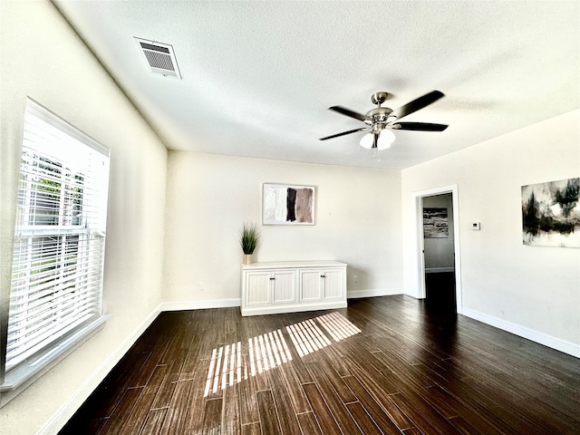 unfurnished living room with ceiling fan, dark wood-type flooring, and a textured ceiling