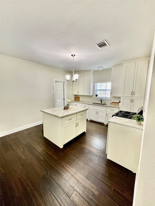 kitchen featuring white cabinetry, sink, dark hardwood / wood-style flooring, pendant lighting, and a kitchen island