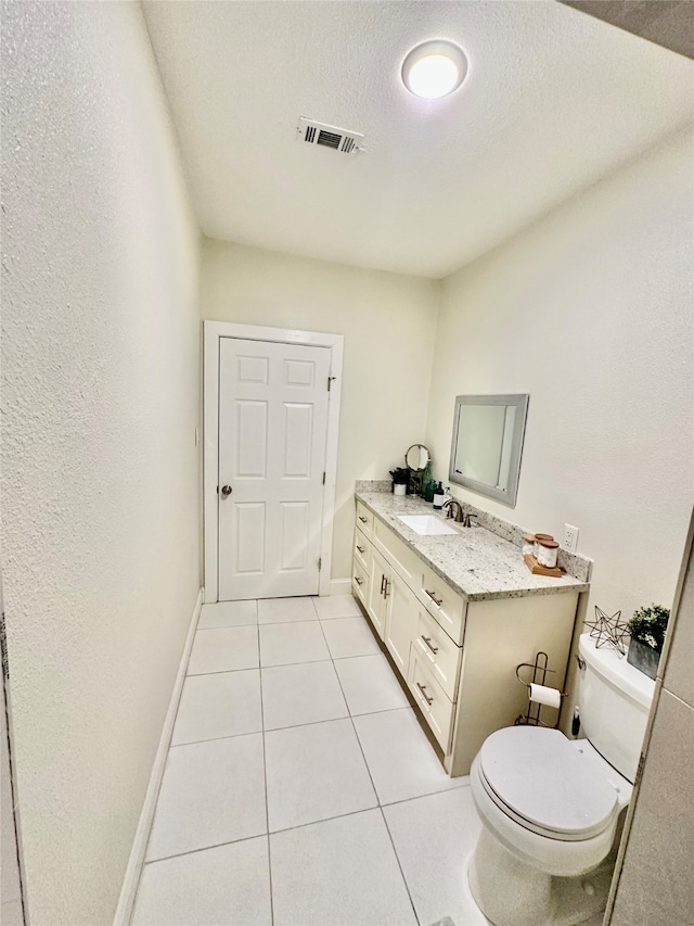 bathroom with tile patterned flooring, vanity, toilet, and a textured ceiling